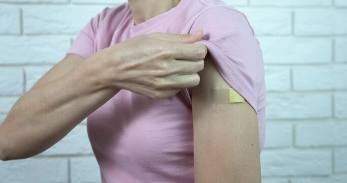 Getting a vaccine for coronavirus. A woman getting a vaccine and show her hand with band-aid.