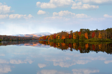 Price lake in North Carolina with Godfather Mountain in background. Fall colored trees and sky reflecting on the lake water.