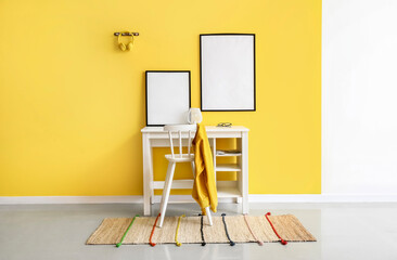 Modern workplace with blank frames near yellow wall