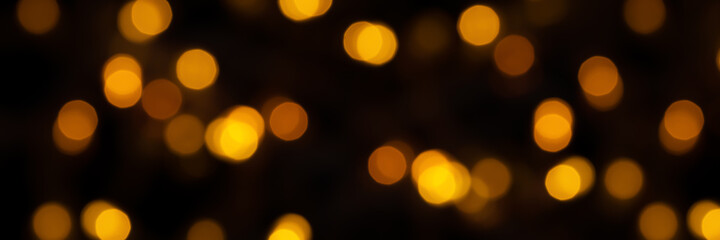 Banner of defocused bokeh lights on black background, an abstract naturally blurred backdrop for Christmas eve or birthday party. Festive light texture. Gold garland in blur. Overlay effect for design