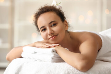 Obraz na płótnie Canvas Young African-American woman lying on couch in spa salon