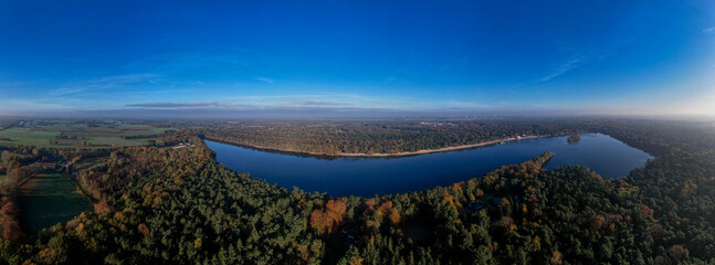 Horse head shaped De IJzeren Man lake surrounded by autumn forest with beaches on its shores. Aerial Dutch panorama landscape scenery.