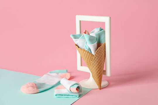 Creative composition with waffle cone, socks and empty picture frame on color background