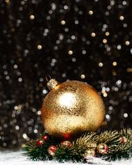 Christmas decorations view of gold evening ball with gold glitter on it in christmas wreath with red berries on dark background with silver and gold colors bokeh. Holidays concept copy space.