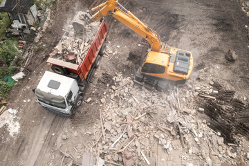 Excavator bucket loads industrial debris into truck. Process of demolishing and destruction old...