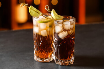 Glasses of tasty Cuba Libre cocktail on table in bar