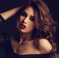 Beautiful bright makeup woman with long brown curly volume hair style, red lipstick, and black...
