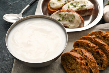Bowl of lard spread and bread pieces on black background