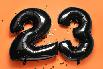 Figure 23 made of balloons and confetti on orange background