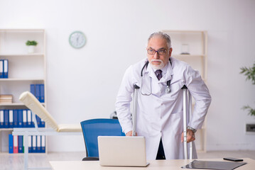 Obraz premium Leg injured old male doctor working in the clinic