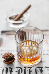 Glass of cold chestnut whiskey on light background