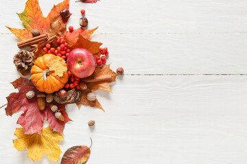 Beautiful autumn composition with natural forest decor, pumpkin and apple on light wooden background