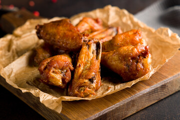 Buffalo chicken wings on the board on dark stone table close up
