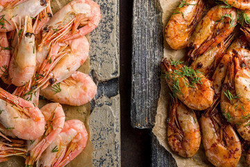 boiled and roasted shrimps with lemon and greens on the board on concrete brown table top view