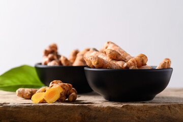 Fresh turmeric in a bowl on wooden with white background, Food ingredients in Asian food and used in beauty spa and herbal medicine