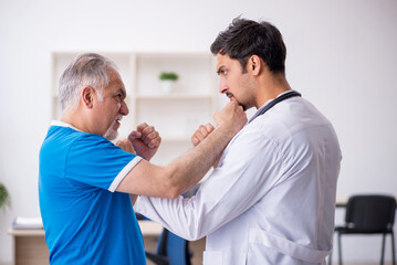 Obraz premium Old male patient visiting young male doctor