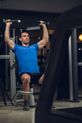 young man exercising lats on machine