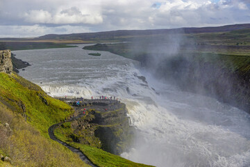 Southwest Iceland: Visitors on a misty overlook at Gullfoss (Golden Falls), the most famous waterfall in Iceland. Water from the Langjokull glacier flows into the Hvita (White) River.