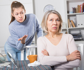 Young woman trying to talk with her offended mature mother