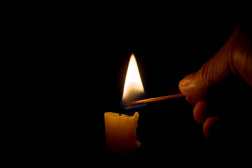 Burning candle in the darkness. Lighting candle with match.