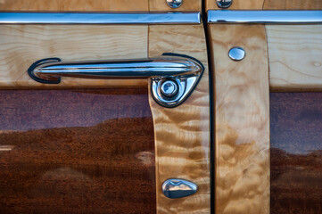 Vintage woody automobile showing the detail just the door handle isolated with wood panelling and...