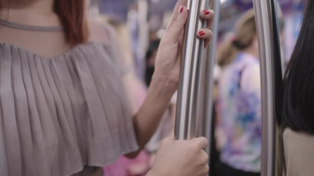 Close up a female red fingernails hand holding on metal rail to prevent from falling, safety equipment on public transportation, domestic life, a risk of contamination to infectious covid-19 diseases