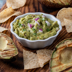 Close up of a bowl of homemade guacamole served with tortilla chips.
