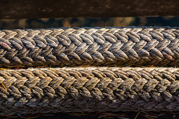Fototapeta na wymiar close up of two thick ropes near the dock with tear and ware under the sun
