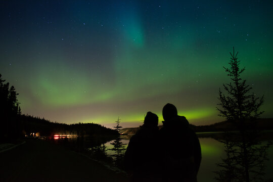 Couple Enjoying The Northern Lights In Whitehorse, Yukon(Canada).