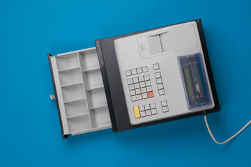 Top view of an open empty cash register on a blue background. Retro mechanism for accounting for...