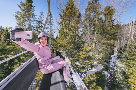 Ski holidays - Woman skier in ski lift doing selfie photo or video using phone. Ski winter vacation concept. Skiing on snow slopes in mountains, People having fun on snowy day. Winter sport activity.