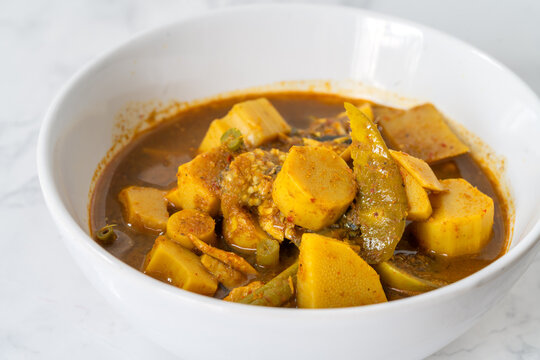 Kaeng tai pla or spicy and salty curry sauce made from fermented fish entrails and vegetables, herbs, traditional Thailand food from the southern. Curry in white bowl on marble white table.