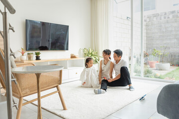 Hermosa familia asiática en su hogar disfrutando un día juntos sentados en la alfombra blanca de...