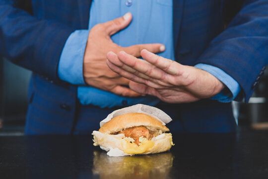 Indigestion of the intestines from poor-quality food. Diarrhea concept Businessman having stomachache because of eating junk food. A man who has eaten too much refuses a burger