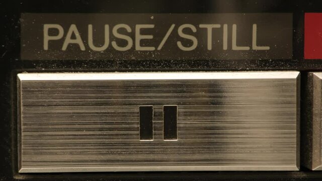 Extreme close up of buttons on an old antique or vintage VCR.  Pushing the pause button.