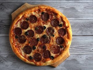 pepperoni pizza with salts and olives on a gray background
