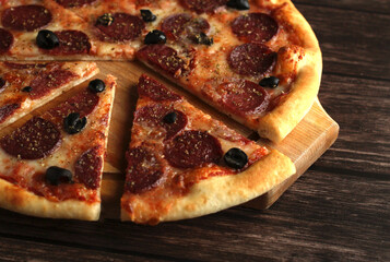pepperoni pizza with sausage and olives on a dark wooden background