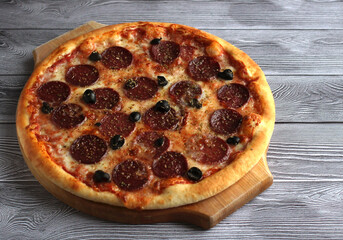 pepperoni pizza with salts and olives on a gray background