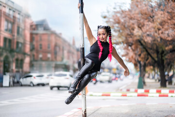 Young sports girl athlete dancing on a pole. Athletic holding a pose on a pole set outdoors. - Powered by Adobe