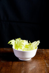 Cabbage in the white bowl and wooden background.