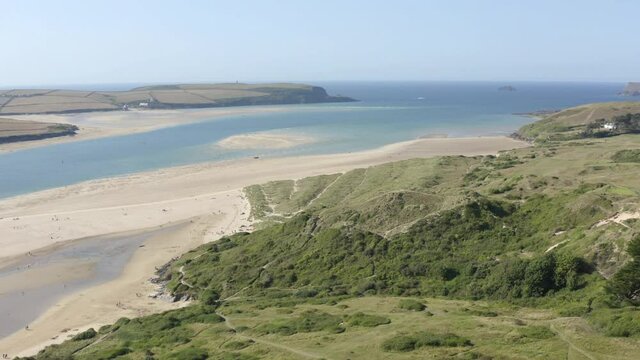 Cinematic drone and aerial footage over Porthtowan Beach in North Cornwall. Green seas and blue skies and surfers enjoying the waves.Flying over beautiful sandy beach, aerial seaside landscape.