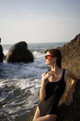 woman in swimsuit sunglasses ocean rocks posing