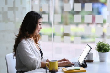 Side view businesswoman working with laptop computer in bright office.