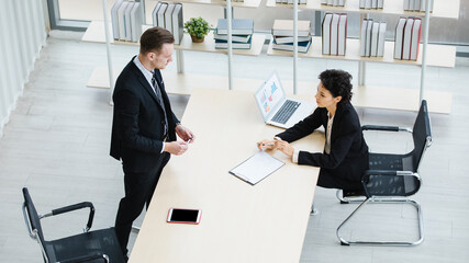 Millennial Caucasian successful thoughtful businessman and businesswoman colleague teamwork in formal suit working togeterh discuss brainstorming solution ideas at company workplace