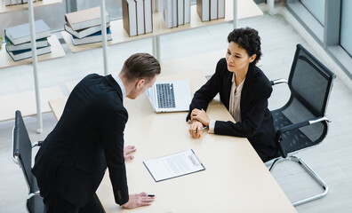 Millennial Caucasian successful thoughtful businessman and businesswoman colleague teamwork in formal suit working togeterh discuss brainstorming solution ideas at company workplace