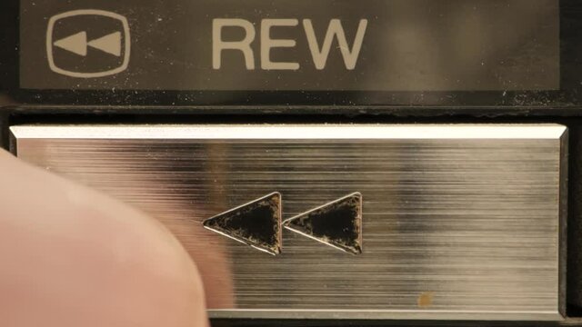 Extreme close up of buttons on an old antique or vintage VCR pushing the rewind button