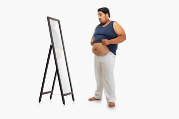 Portrait of a fat man looking at bellyfat in mirror with surprise against plain background.