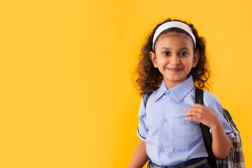 PORTRAIT OF A HAPPY GIRL IN SCHOOL UNIFORM LOOKING AT CAMERA