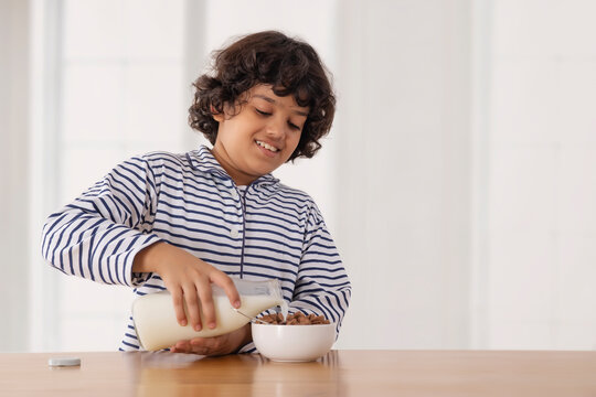 A boy pouring milk into a bowl full of chocos