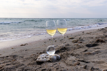 Romantic glass of white wine, on the sea beach. Wine tasting and relaxation at the resort